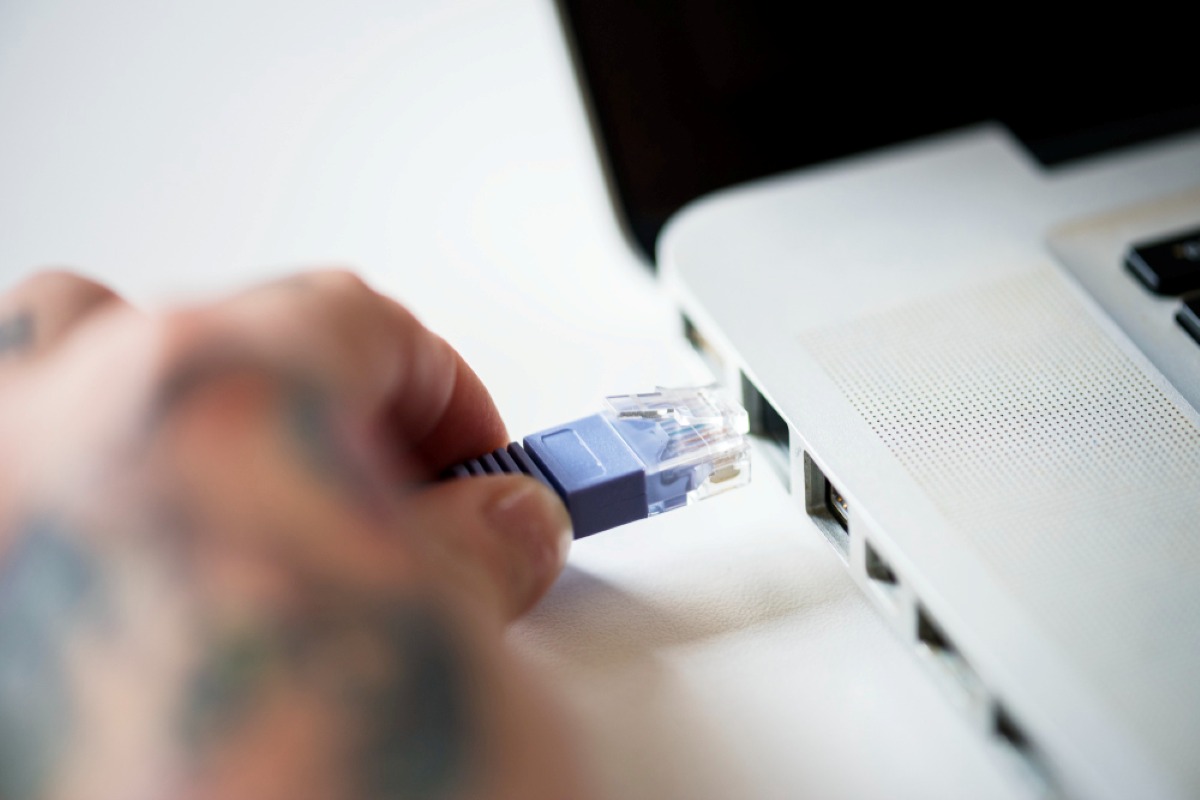 persona conectando un cable ethernet a su ordenador